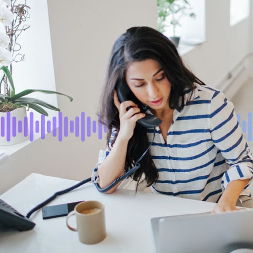 Photo of a woman in an office talking on her desk phone while typing on her computer. In the background, a series of small vertical purple-gradient lines run across the screen.