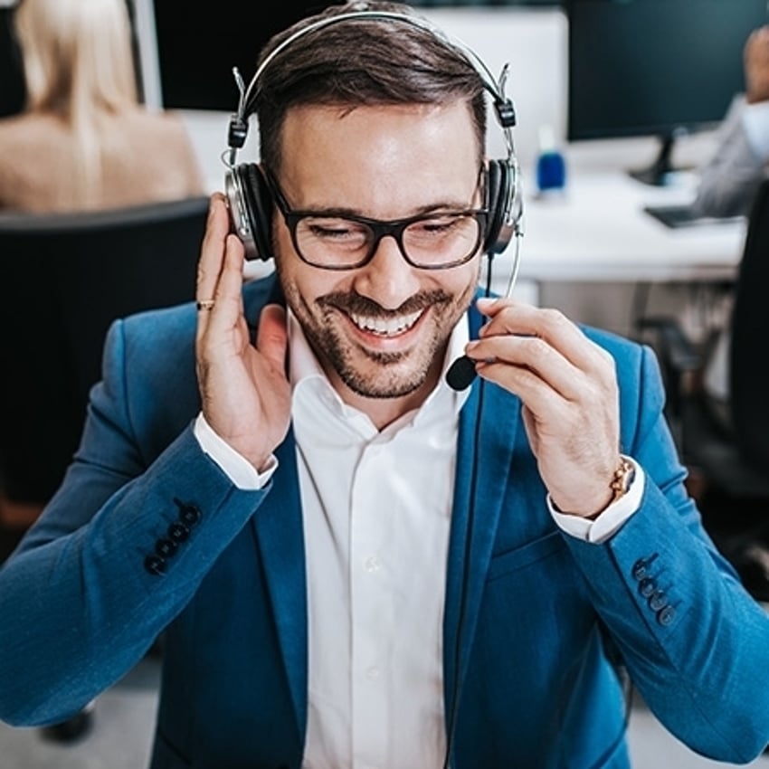 Atractivo agente de servicio al cliente haciendo telemarketing en oficina de call center.